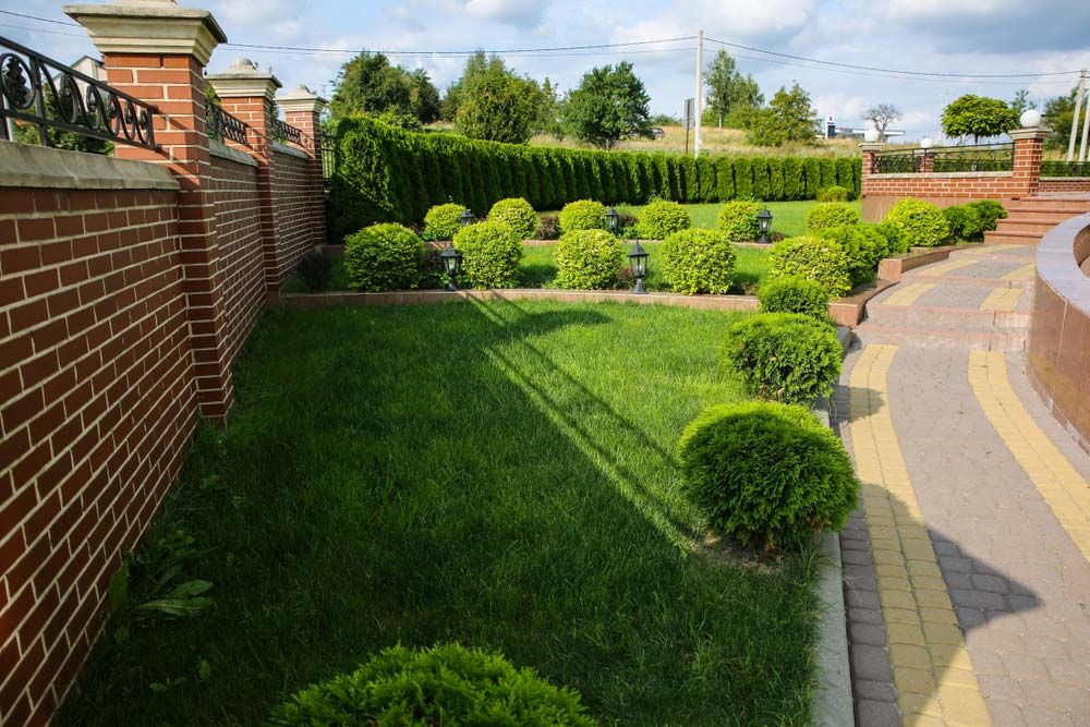 A Brick Wall Surrounds a Lush Green Garden — B & C Yard Improvements in Nyngan, NSW