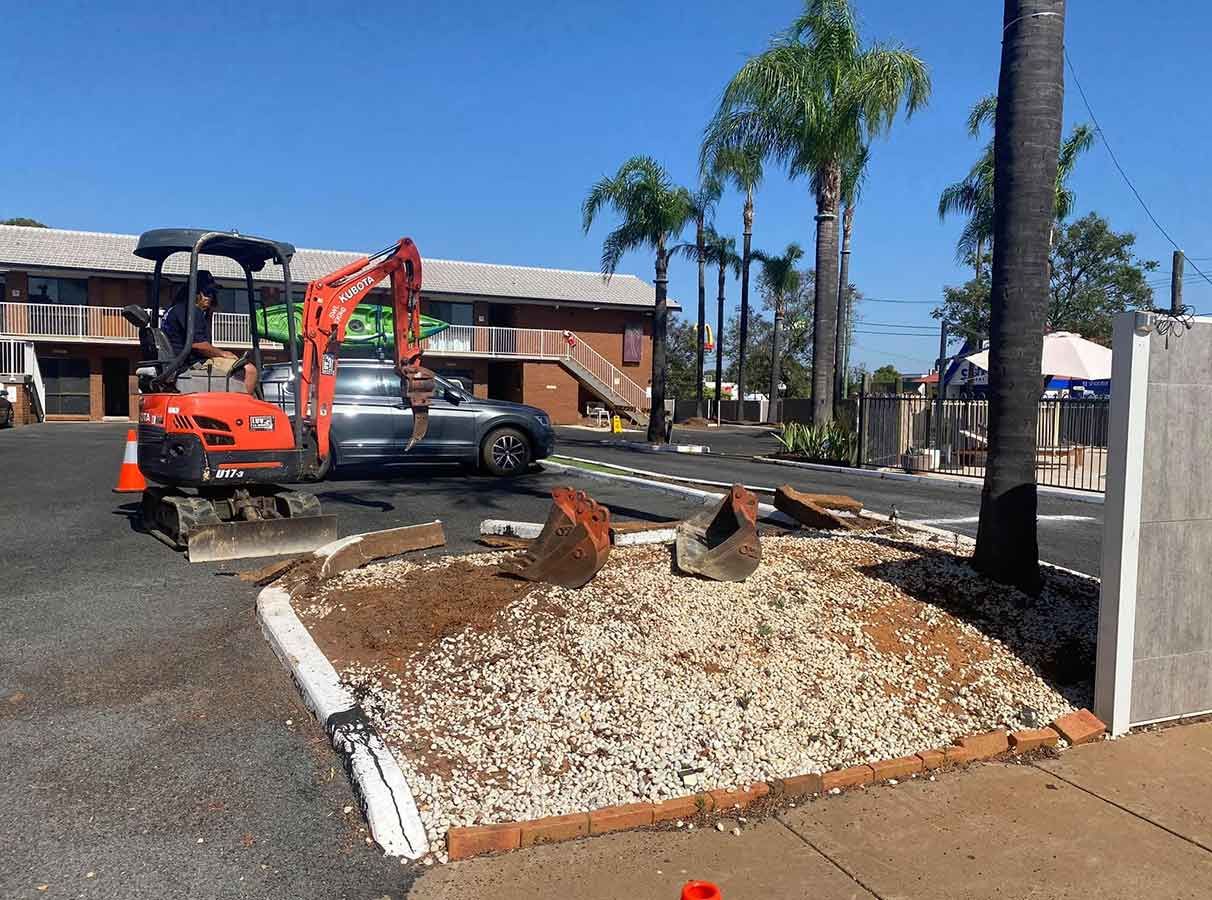 A Small Excavator is Sitting on the Side of the Road in Front of a Building — B & C Yard Improvements in Mudgee, NSW