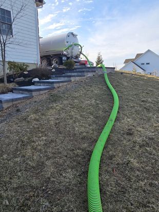 Green hose on gravel sloping yard beside houses under cloudy sky