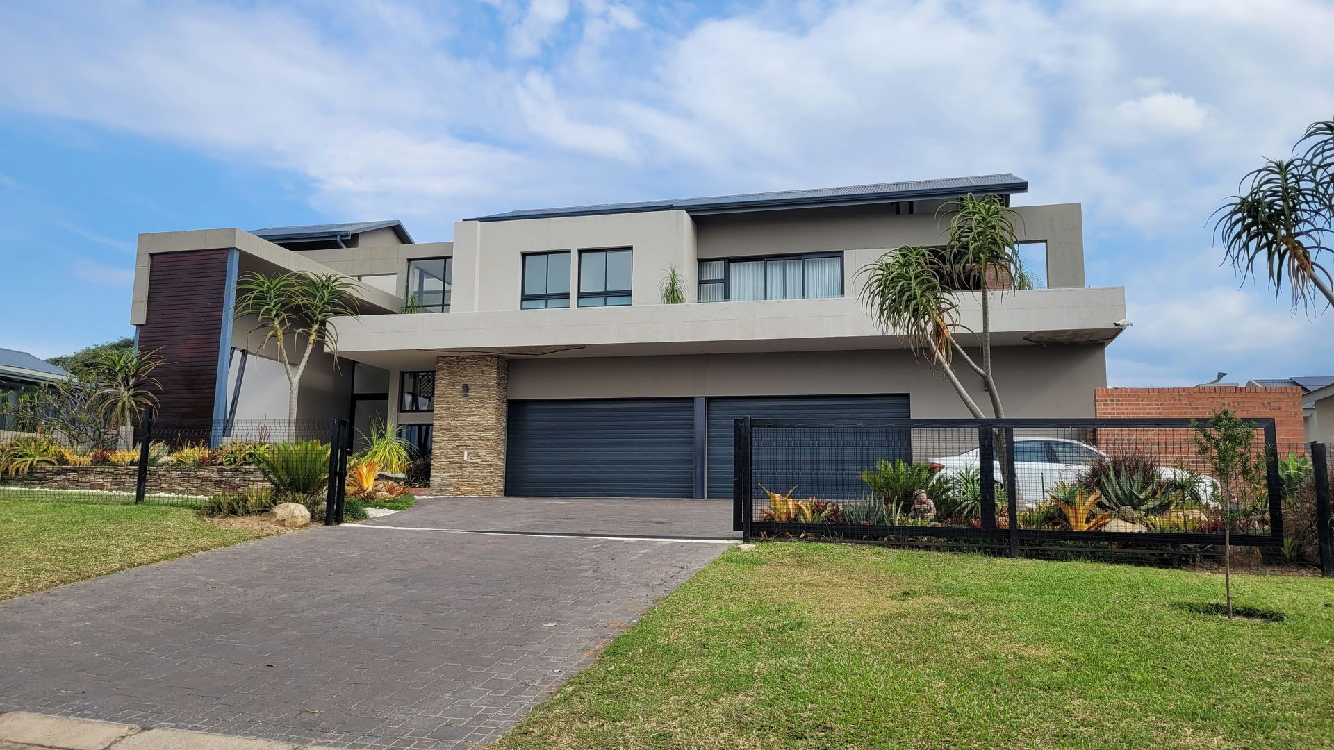 Modern two-story house with a double garage, driveway, and front lawn under a clear sky