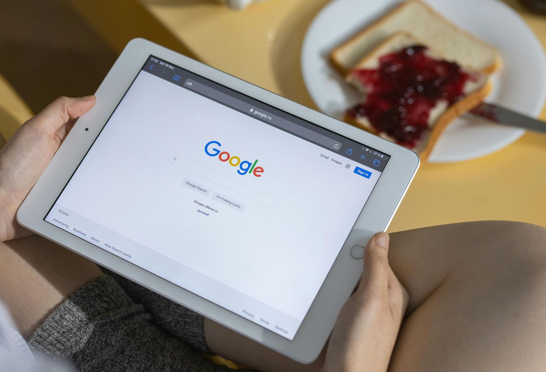 A person is holding a tablet with google on the screen.