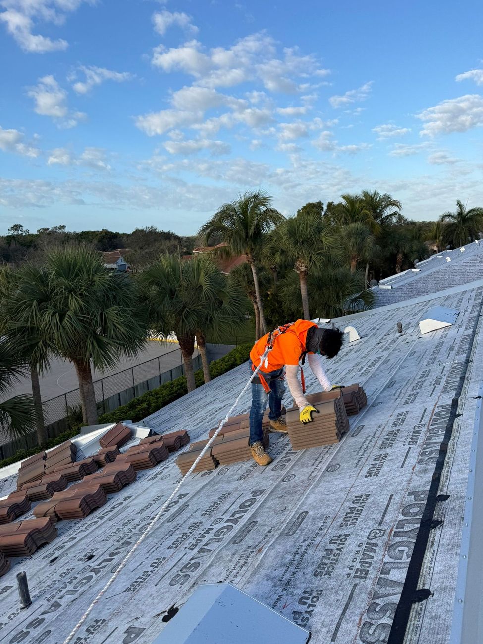 Roofing crew loading roof tiles onto a residential roof deck