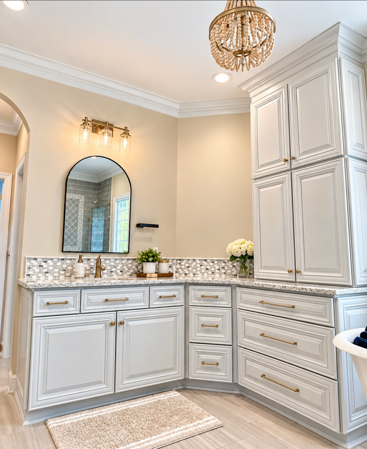 Bright cream bathroom with white vanity cabinets, granite countertop, mirror, and chandelier.