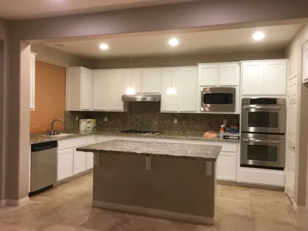 Modern kitchen with white cabinets, granite island, and built-in stainless steel appliances
