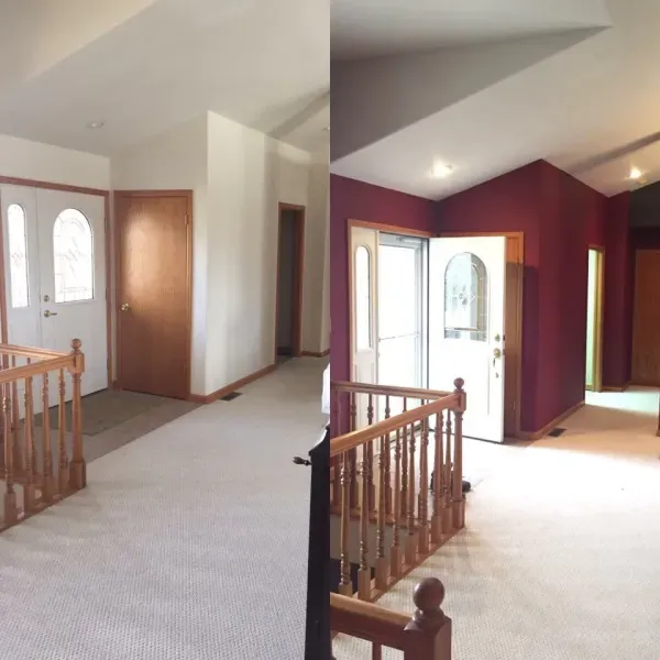 Empty upstairs hallway with carpet, red accent walls, wood railings, and front doors.