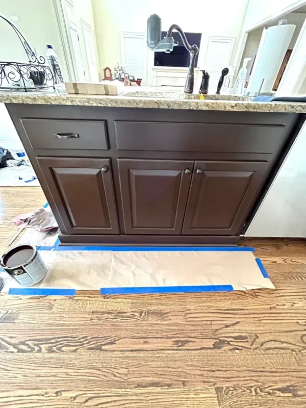 Dark brown bathroom vanity with white countertop and sink, viewed from the front in a kitchen or bathroom space.