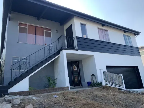 Two-story house with exterior stairs, garage, and sloped front yard