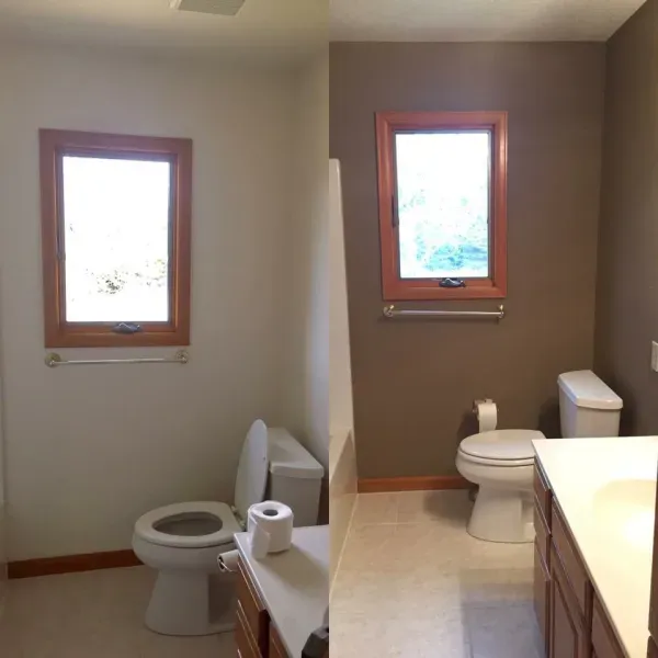 Small restroom with two toilets, two windows, and a sink counter on the right.