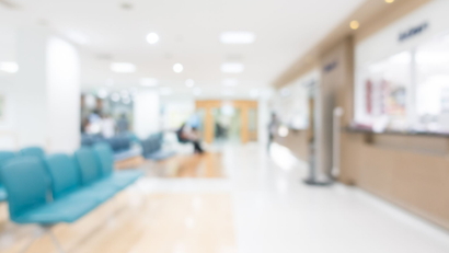 Bright, blurred modern waiting room with teal chairs and a reception desk