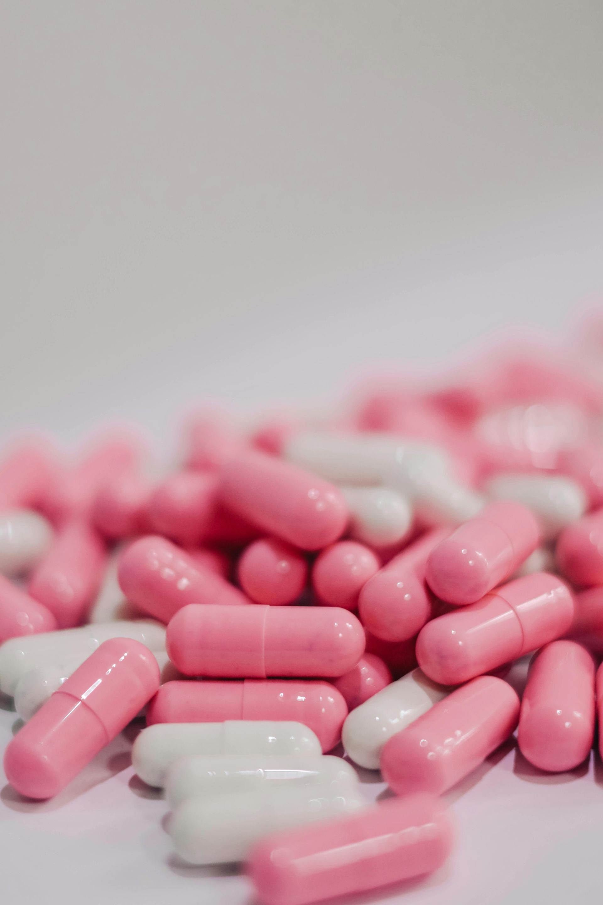 Pile of pink and white capsules scattered on a white surface