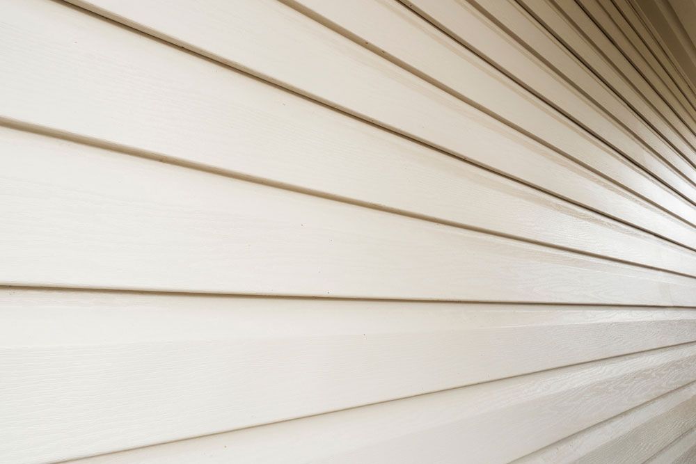 Diagonal beige siding panels with horizontal lines and bright sunlight shadows