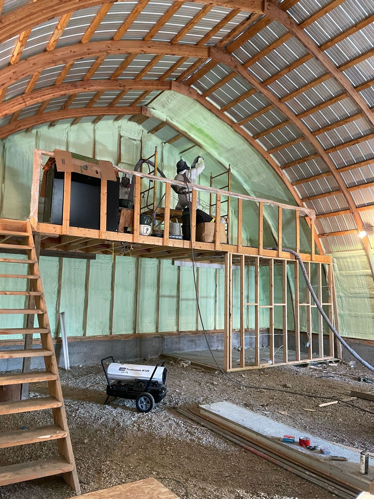 A man is standing on top of a wooden structure in a building under construction.