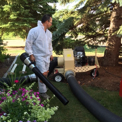 A man in a white suit is standing next to a vacuum cleaner