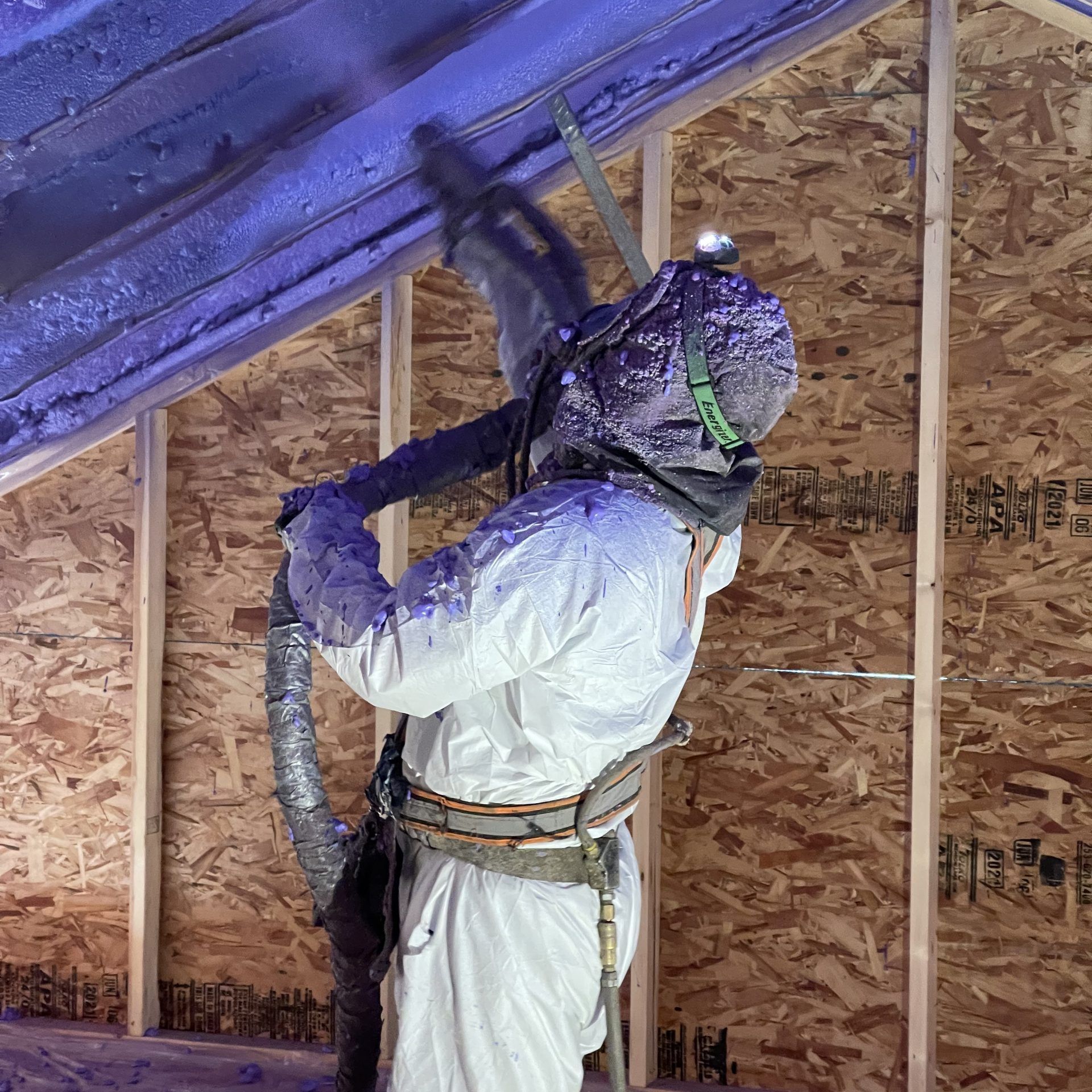 A man is spraying foam on the ceiling of a house.
