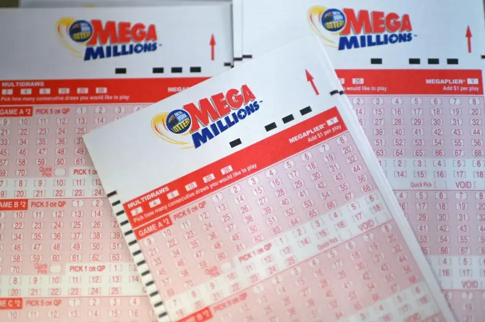 Mega Millions lottery tickets and play slips fanned out on a table with the logo visible