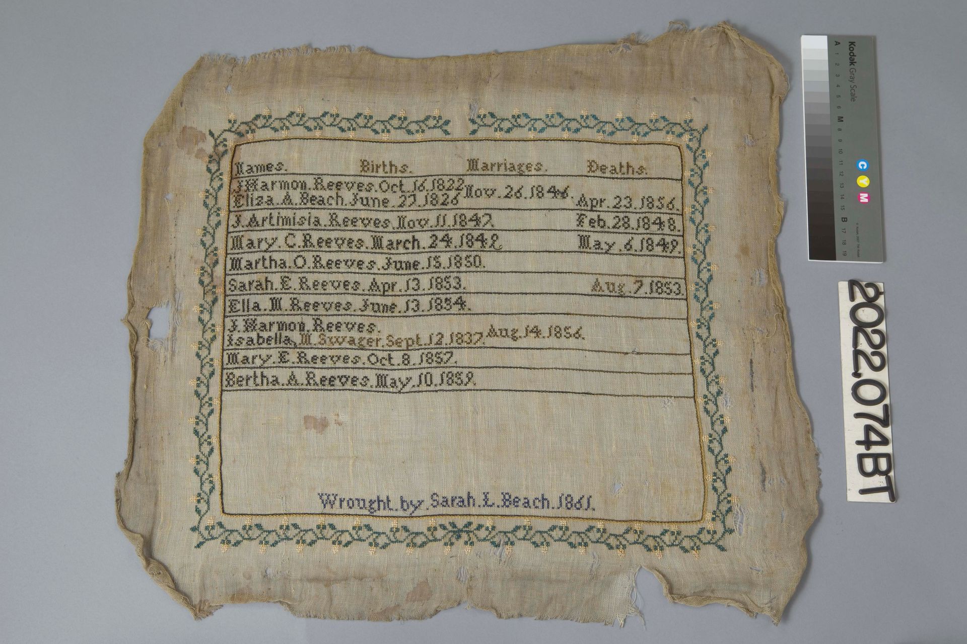 An aged, fragmented US flag with visible stitching and worn fabric is mounted flat on a light brown display board.