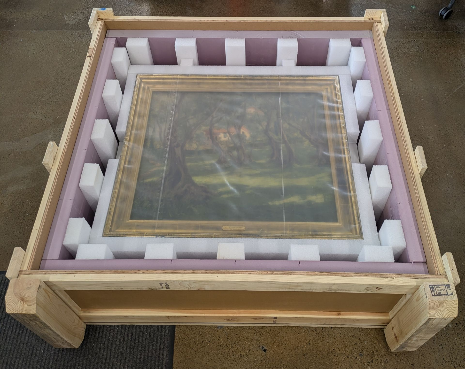Framed artwork packed in a wooden shipping crate with white foam padding