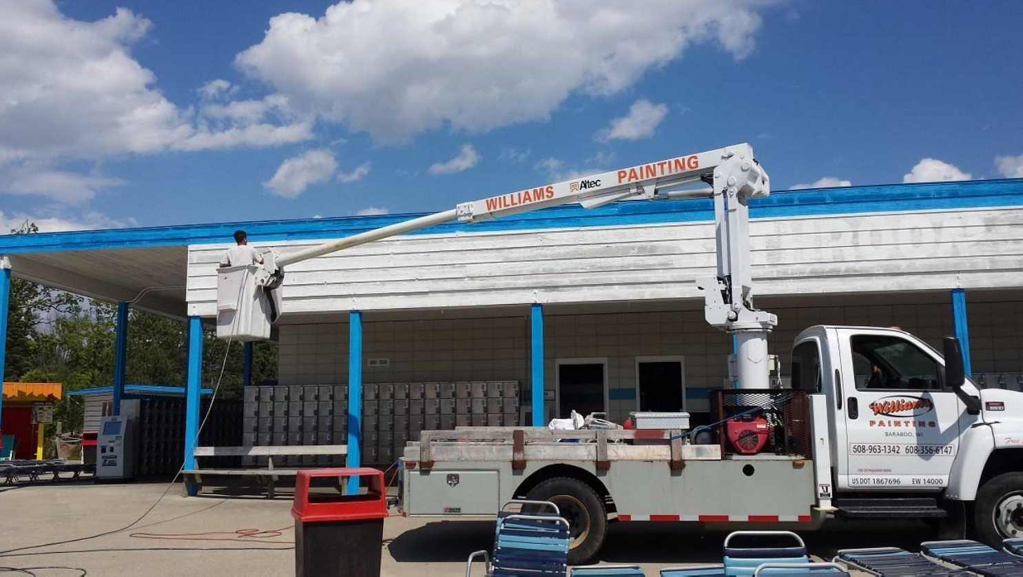 A white truck with a crane on the back is parked in front of a building.