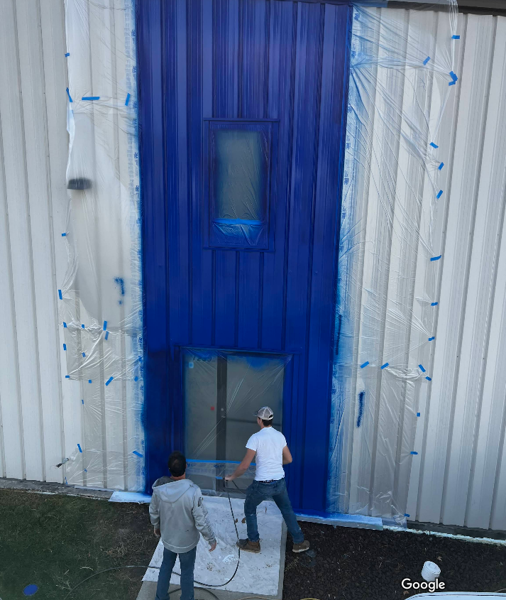 Two men are painting the side of a building blue