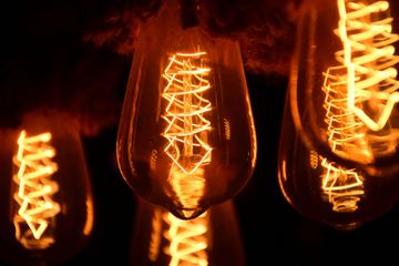 Glowing Edison-style light bulbs with a warm orange glow against a dark background.