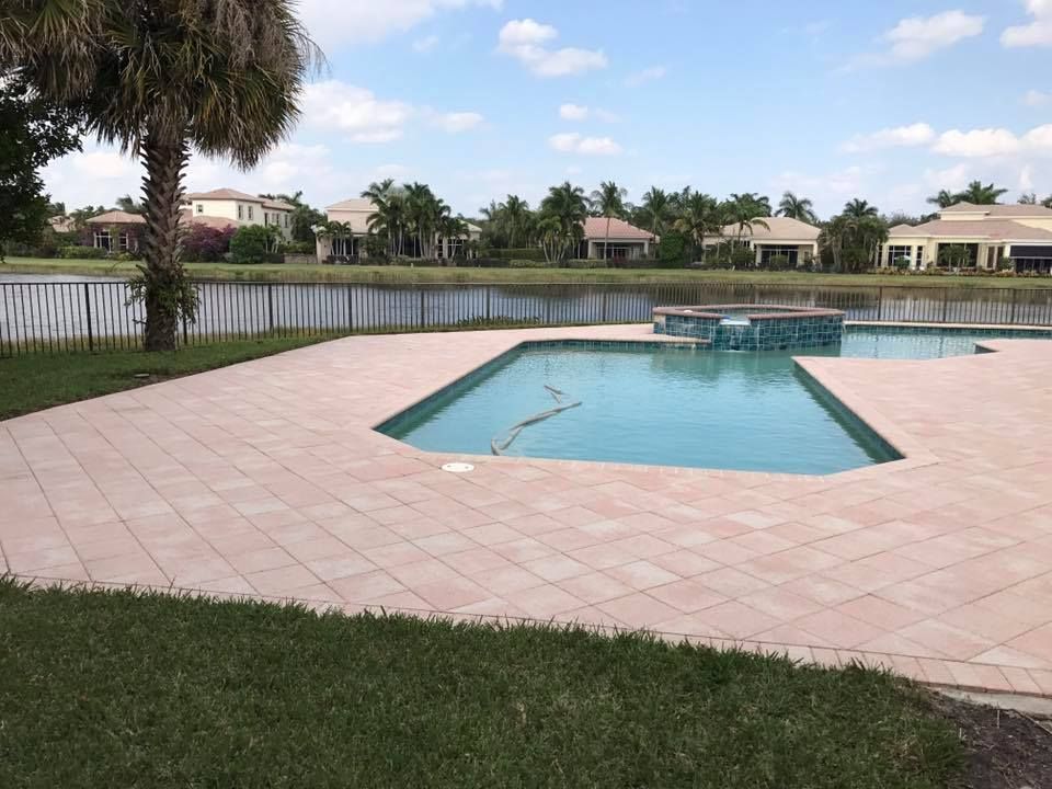 Poolside view of a pool with a lake and houses in the background under a blue sky.
