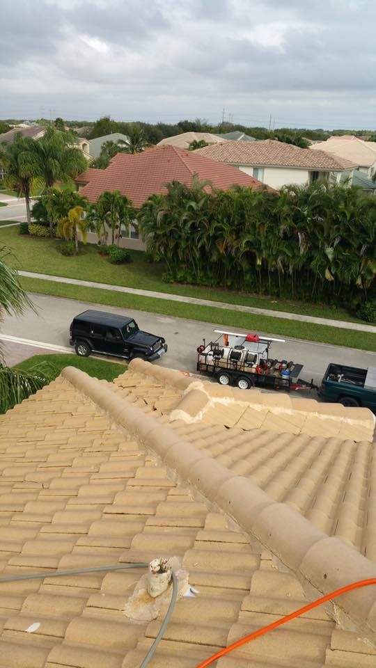 View from a rooftop of a black Jeep with a trailer parked on a street in a residential neighborhood.