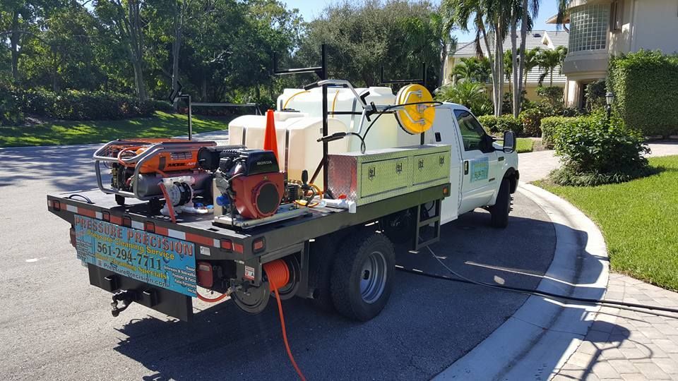 A white flatbed truck with equipment parked on a residential street.