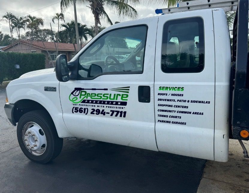 White pressure washing service truck parked outdoors with logo and phone number visible.