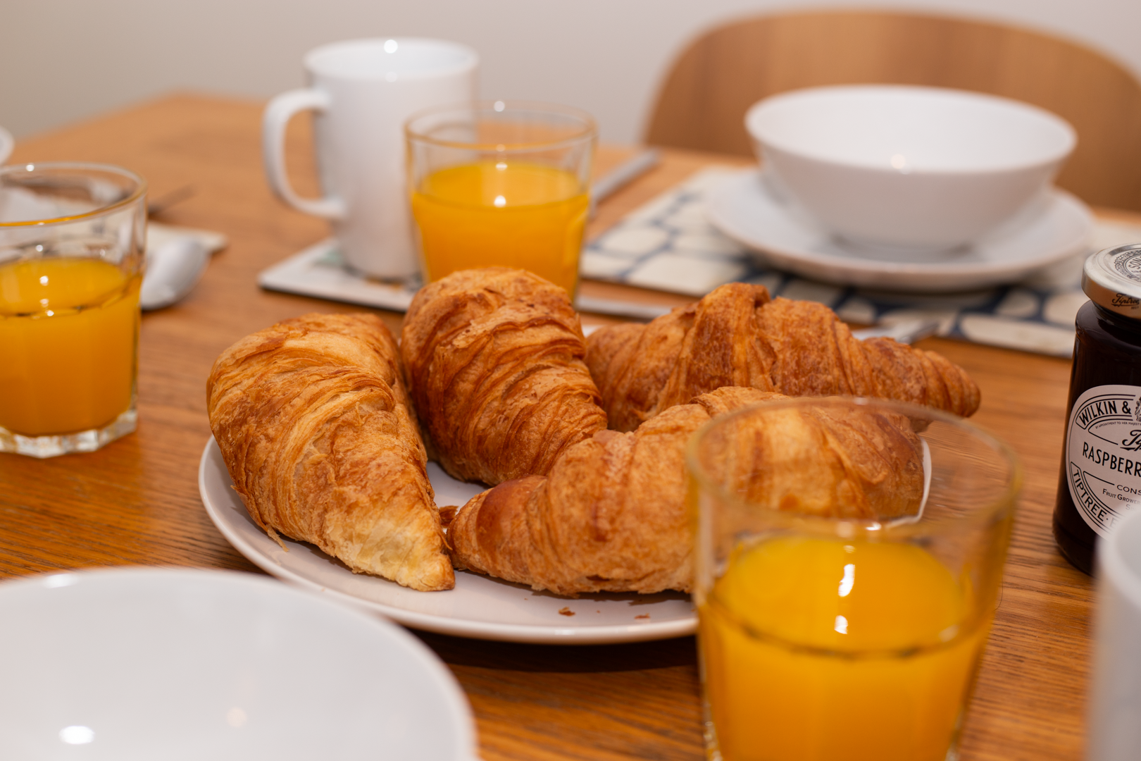 A plate of croissants and orange juice on a table.