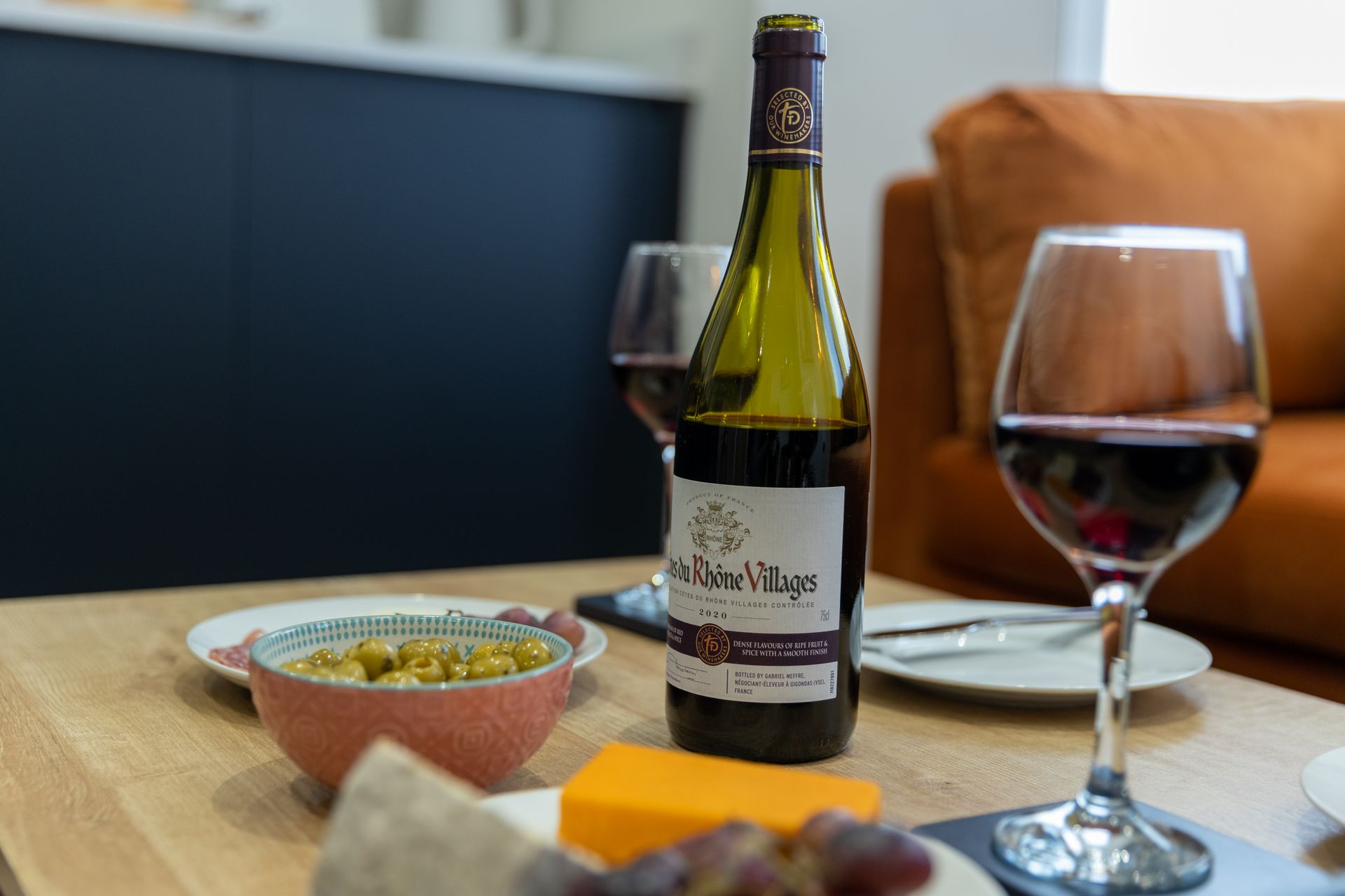 A bottle of wine and a glass of wine are on a table.