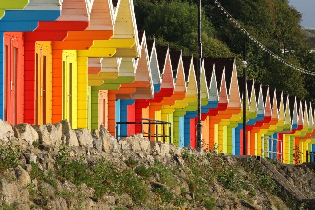A row of colorful beach huts are lined up in a row