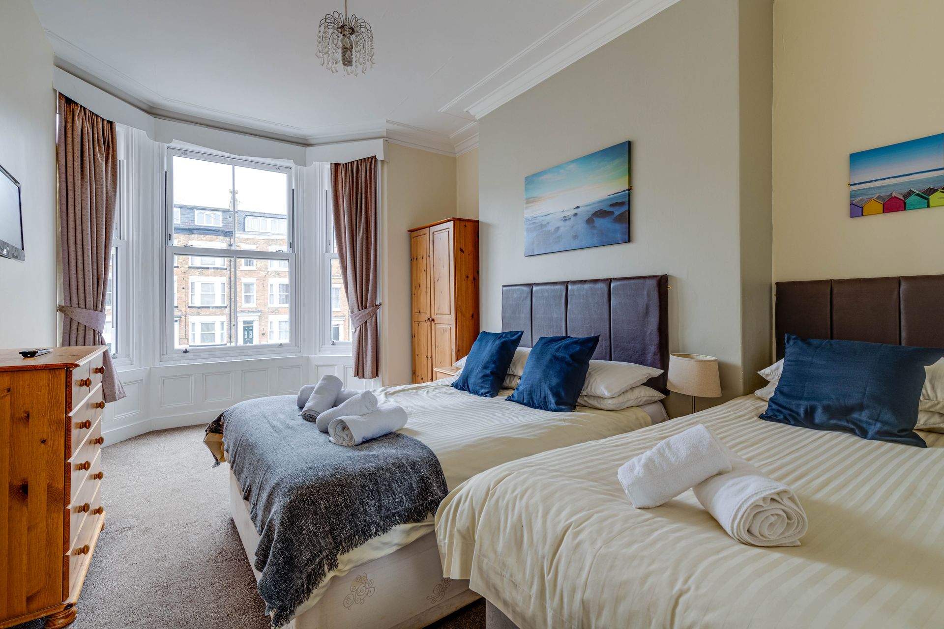 A bedroom with three beds , a dresser , and a window.