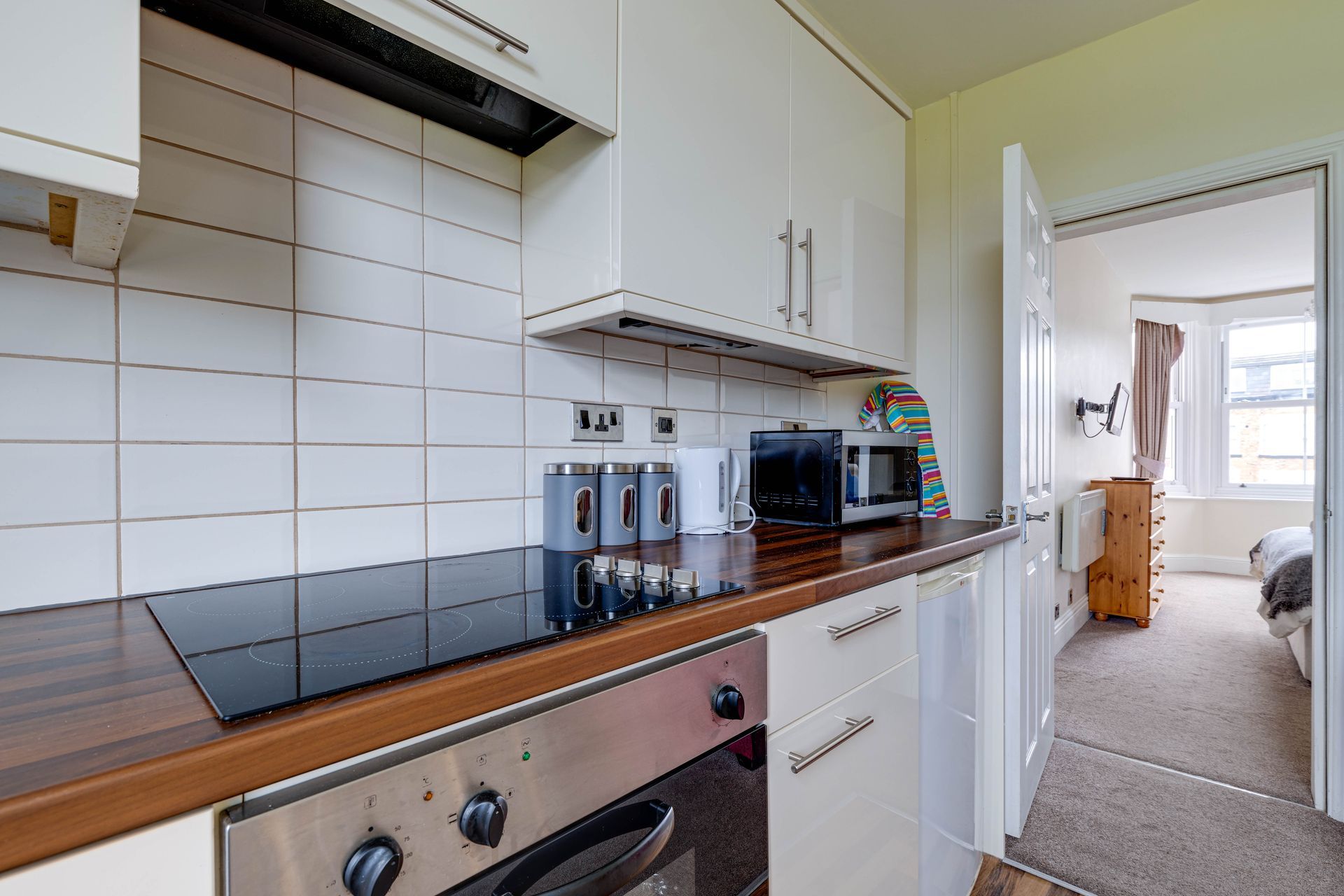 A kitchen with white cabinets , a stove top oven , and a microwave.