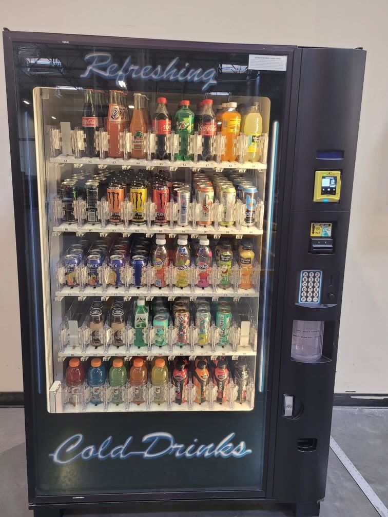 A Row Of Vending Machines Filled With Drinks In A Dark Room.