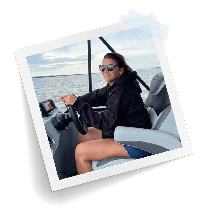 A person wearing sunglasses and a black hoodie drives a boat on open water, shown within a square photo frame.