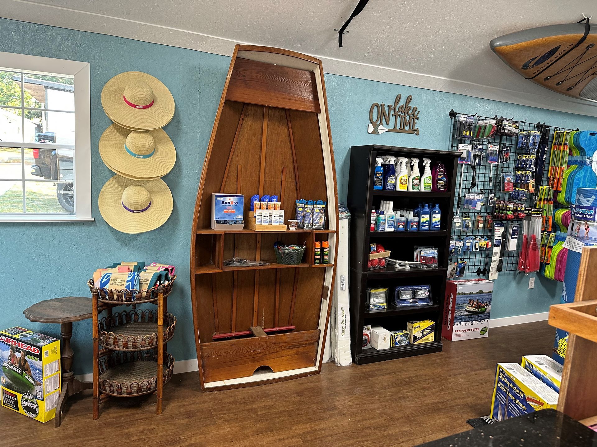 A boat-shaped shelf displays merchandise in a light blue room with a rack of hats and shelves of retail goods.
