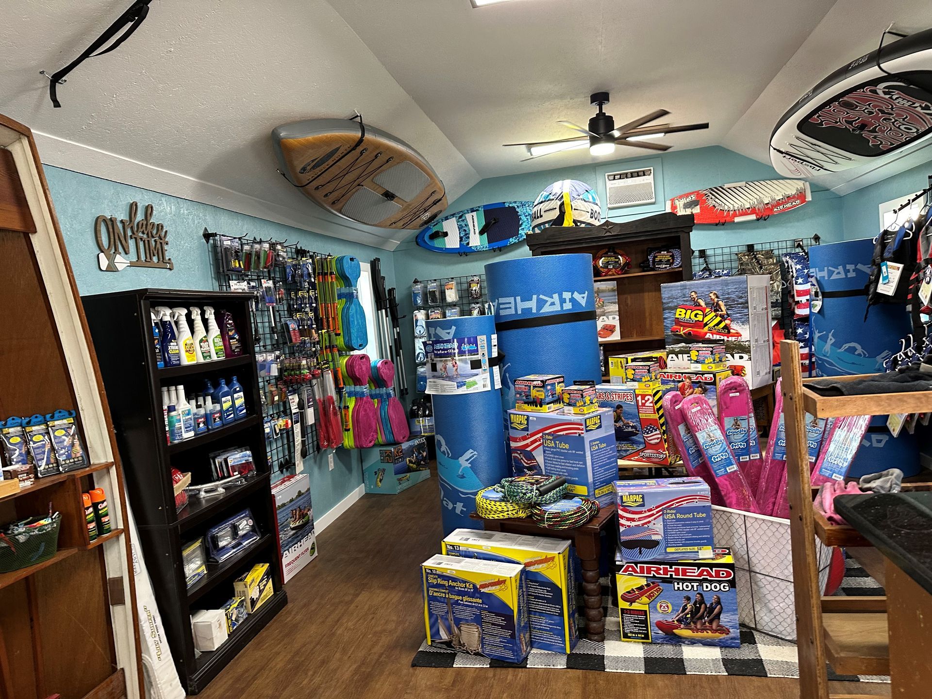 A retail shop interior filled with water sports equipment, including kayaks, paddleboards, and various beach accessories.