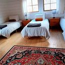 Bright bedroom with two single beds, wooden nightstands, blue lamps, and a red patterned rug