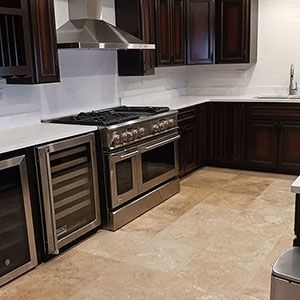 Modern kitchen with stainless steel stove, wine fridge, dark wood cabinets, and beige tile floor