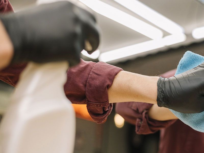 Gloved hands apply a bandage to an outstretched arm in a clinical setting