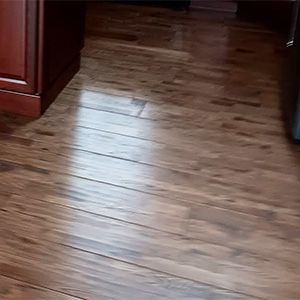 Wooden kitchen floor with a bright reflection of light and cabinets along the edges