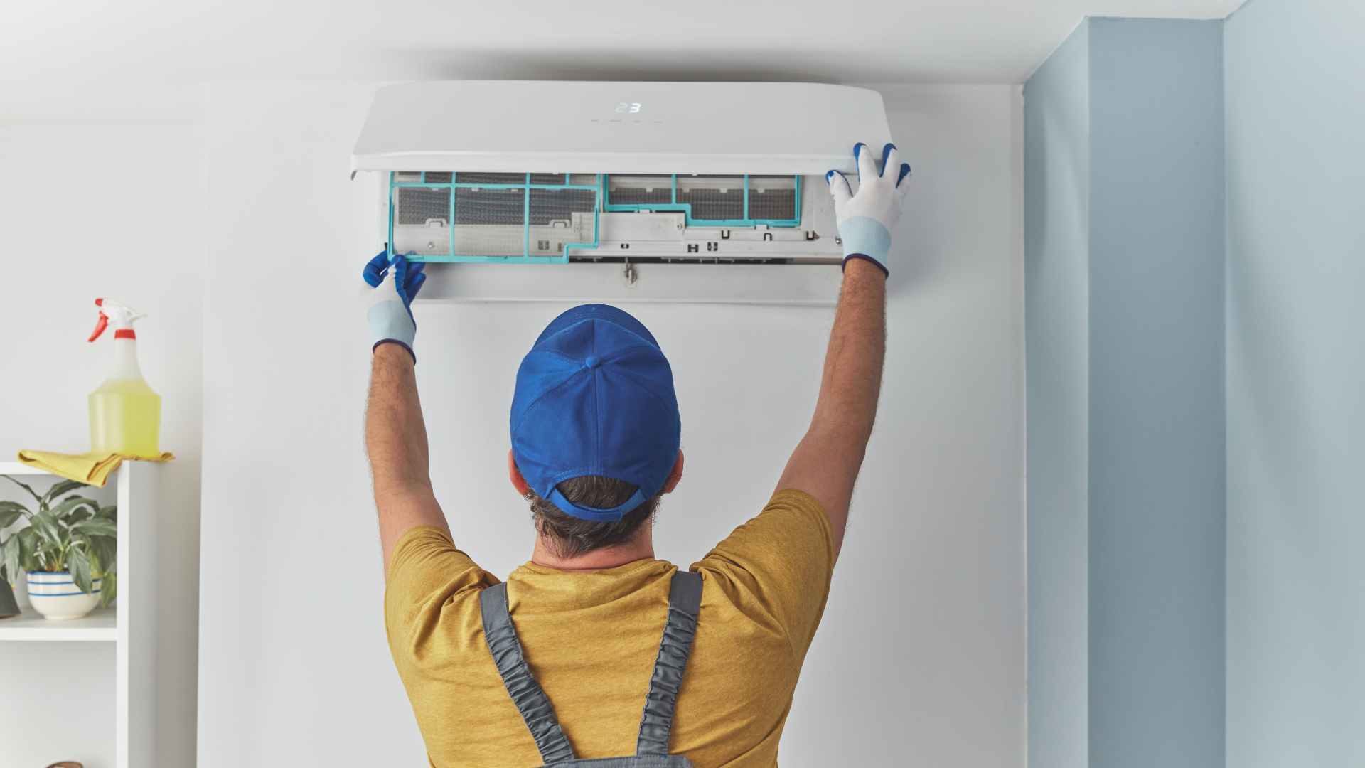 A man is cleaning an air conditioner in a living room.