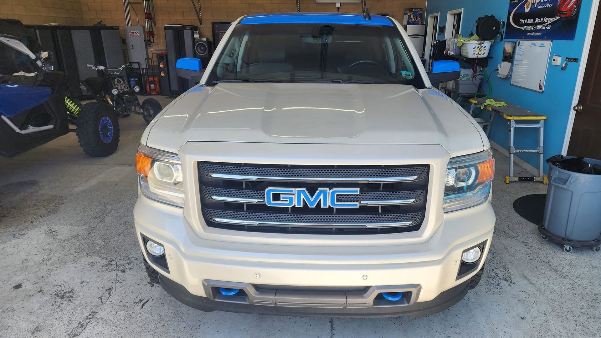 White GMC pickup truck parked in a garage, front view with blue trim details