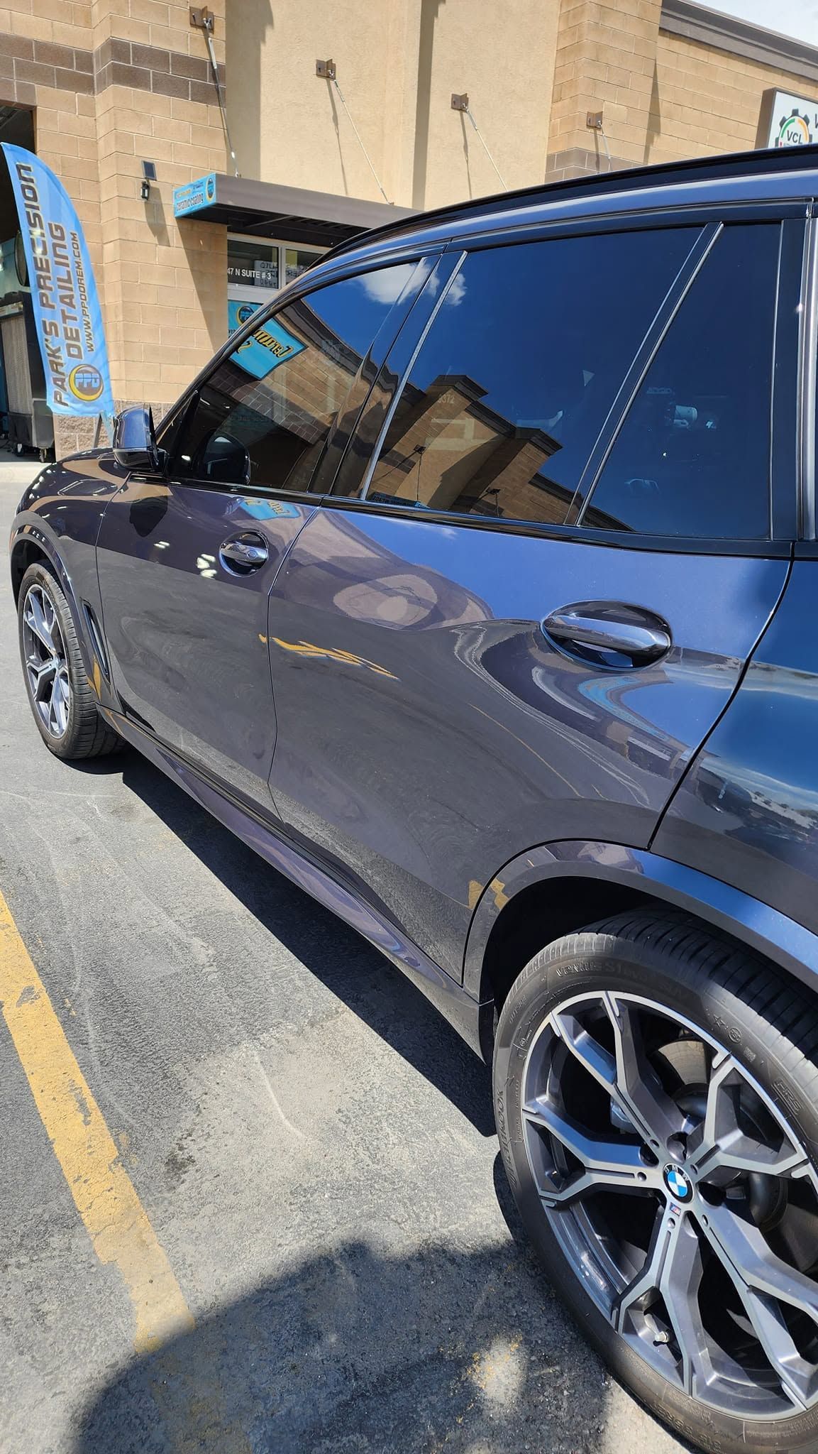 Dark blue SUV parked beside a tan building in a sunny outdoor lot