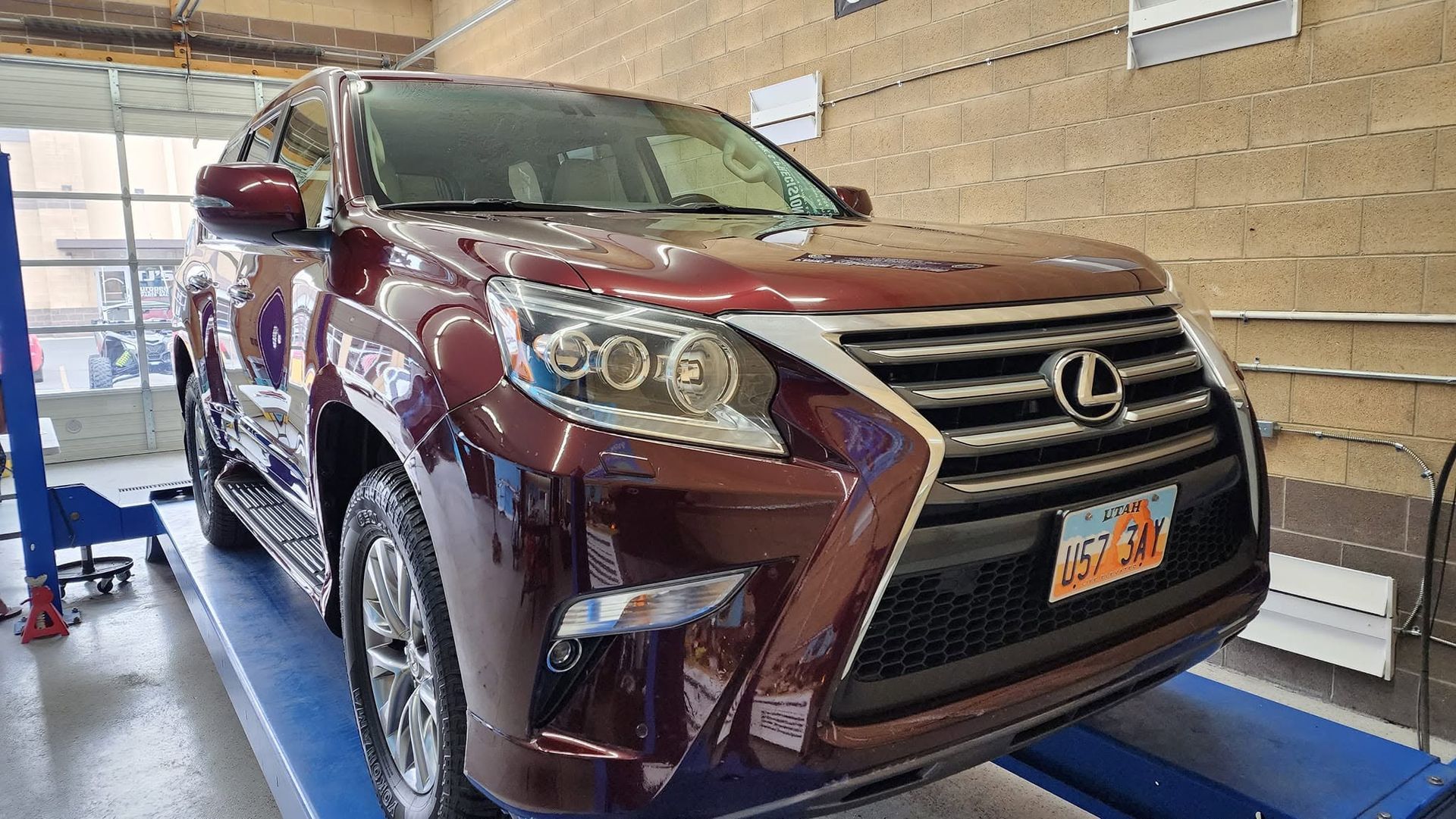 Maroon Lexus SUV on a lift inside an auto repair shop