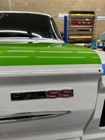 Close-up of a white and lime-green classic car with Camuro SS badge in a garage