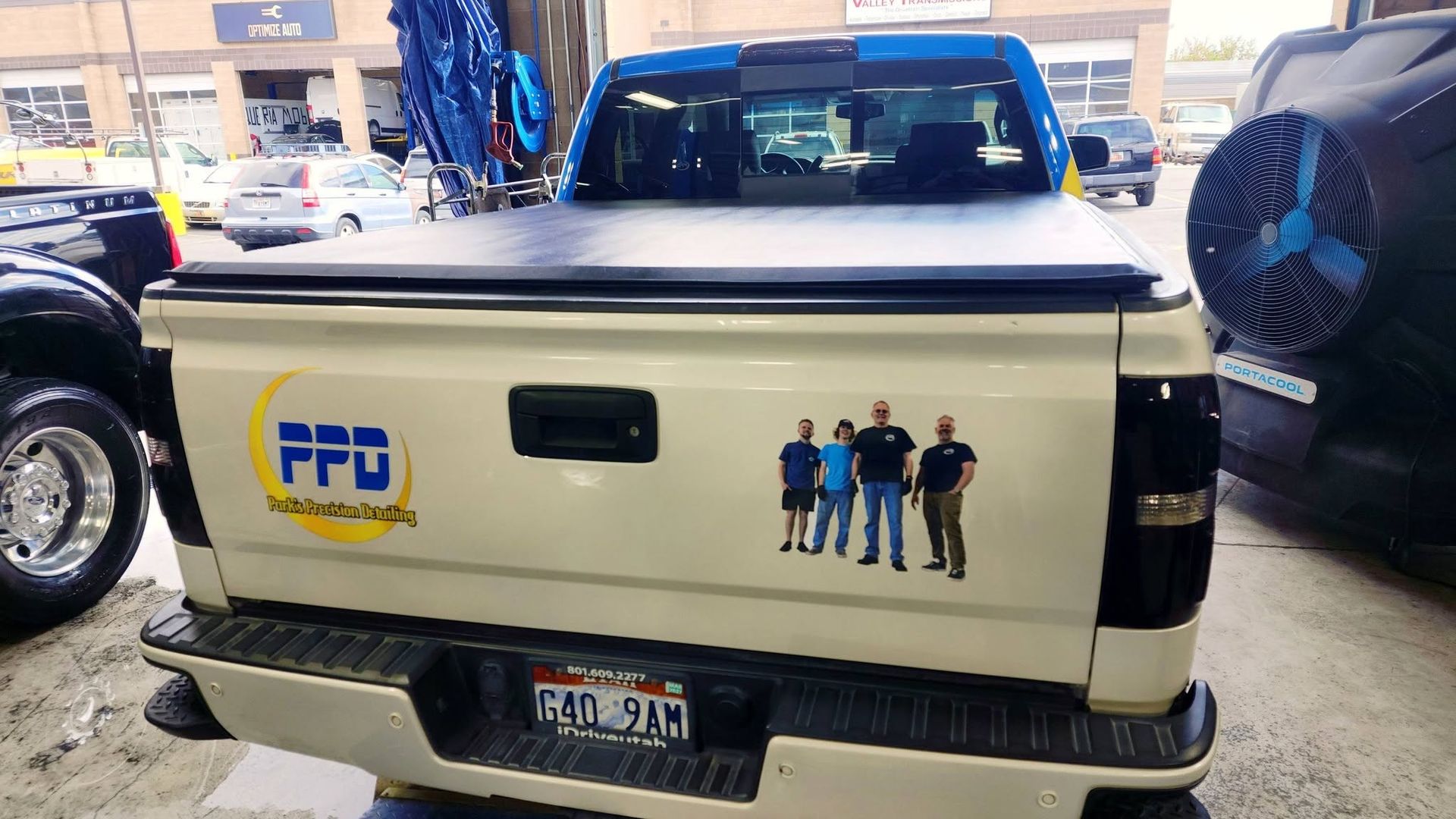 White pickup truck tailgate with PFA logo and cartoon figures, parked in a covered lot