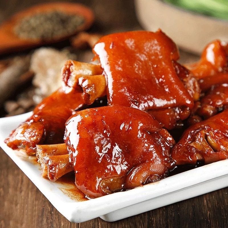 Glazed roasted meat on a white plate, coated in a shiny red-brown sauce.