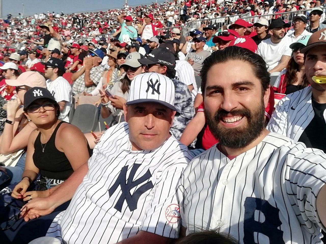Un hombre que lleva un sombrero de Nueva York se está tomando una selfie con otro hombre.