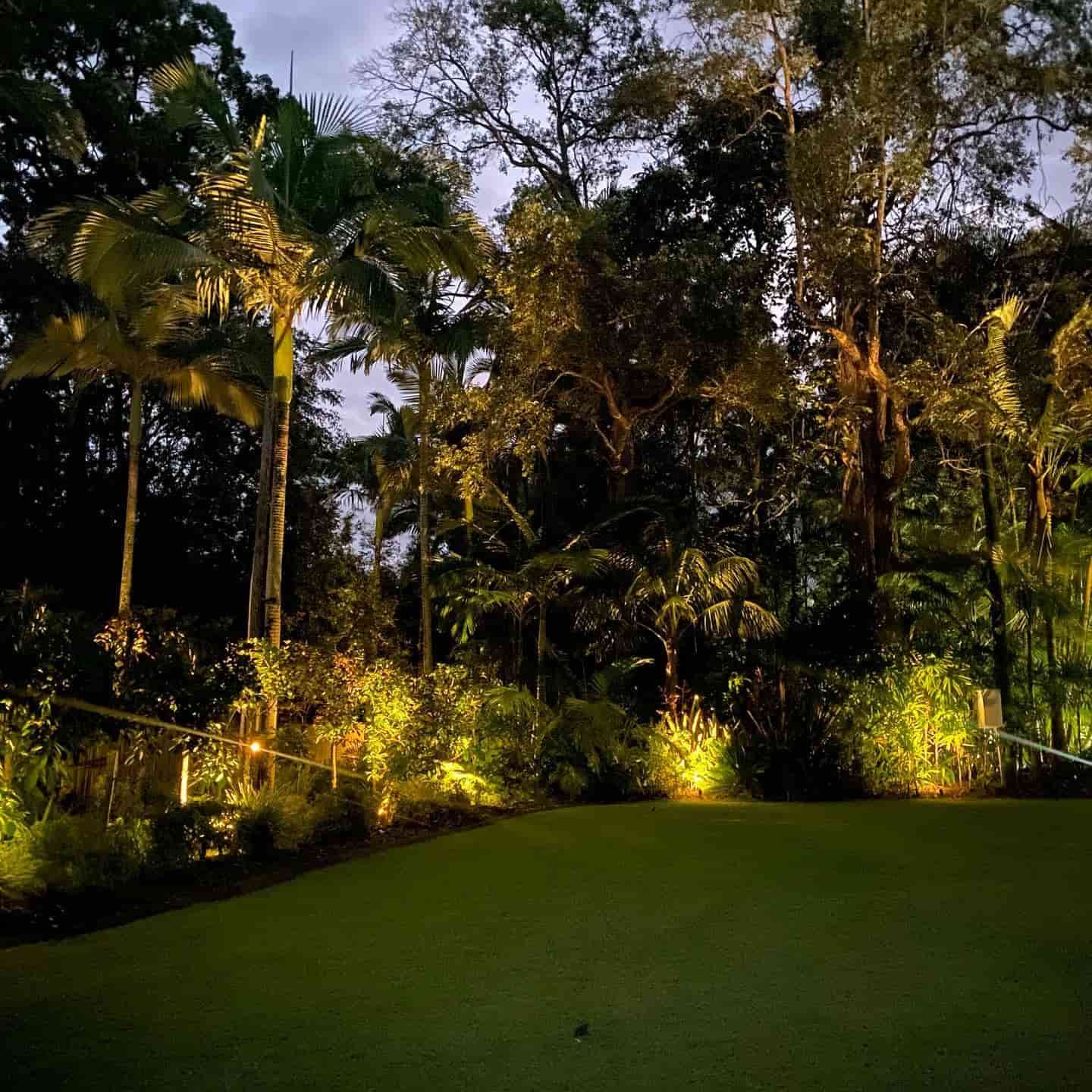 A Lush Green Field Surrounded by Trees Is Lit up At Night — Higgins Electrical in Beerwah, QLD